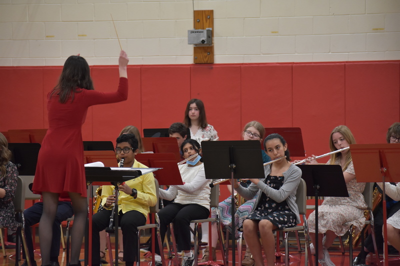 Mrs. Martin directs the 7th and 8th grade band as they play a song. Flutes, clarinets, and a drummer are visible.