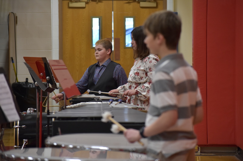 7th grade percussionists focus on their music as they play with the band.  Timpani and xylophone are visible in the picture.