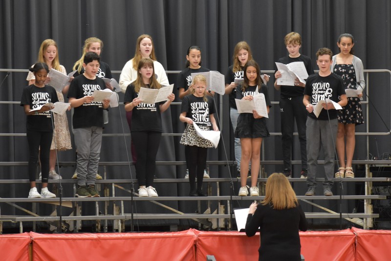 Mrs. LaMantia directs the choir as they sing a song on the stage in the large gym for Bengals Night.