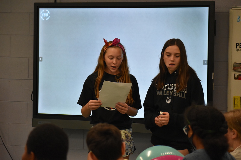 Two students present information to their peers in a classroom as a part of Charity Fest