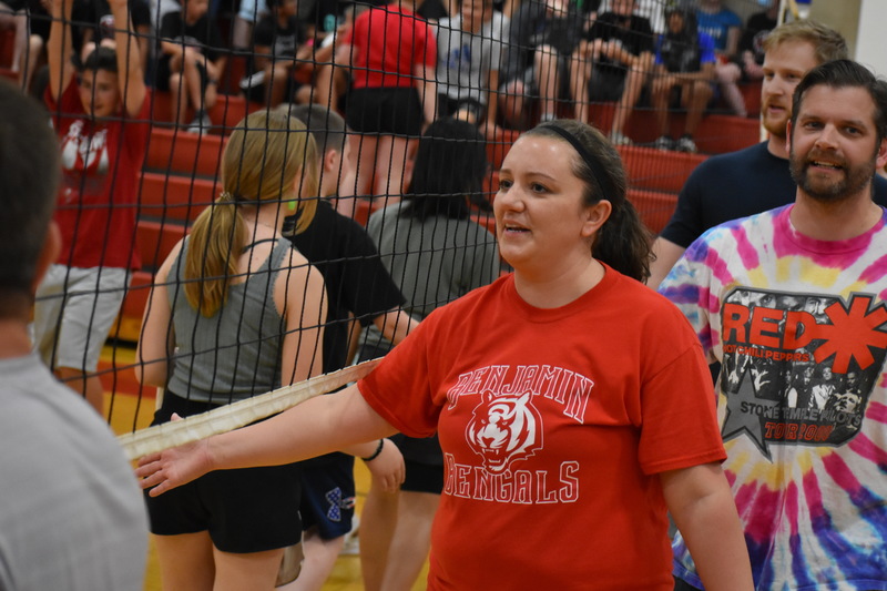 Staff and students give each other fives under the volleyball net after the staff vs. student game