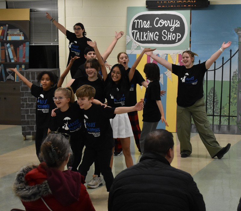 Theatre club students pose and smile at the end of the performance of a song in the Multi-purpose Room at Benjamin Middle School